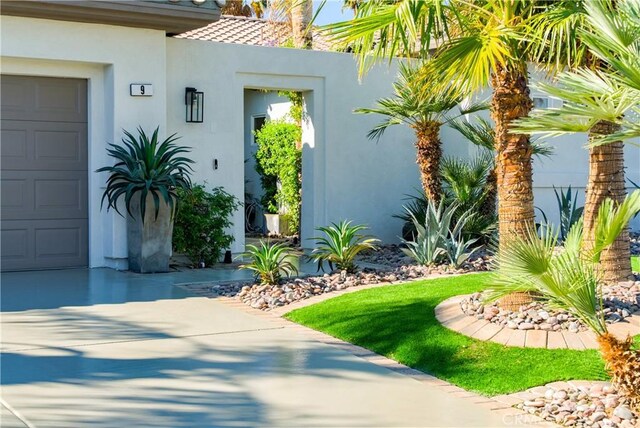 9 Via Dulcinea, Dulcinea, Palm Desert, CA 92260 - doorway to property featuring stucco siding, an attached garage, concrete driveway, and a tiled roof