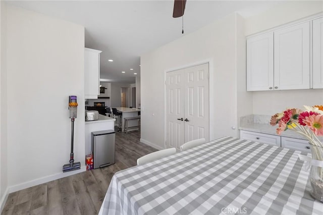 bedroom with wood finished floors, recessed lighting, baseboards, a ceiling fan, and a fireplace