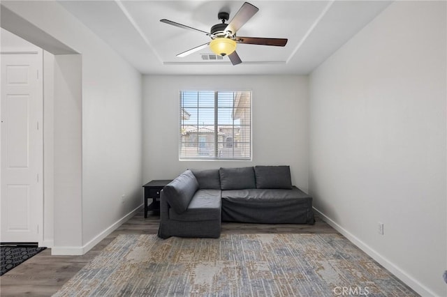 living area with a ceiling fan, wood finished floors, and baseboards