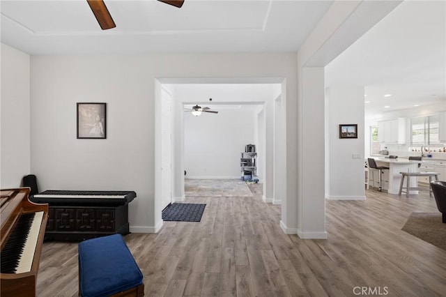 hall featuring light wood-type flooring, baseboards, and recessed lighting