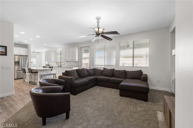 living area featuring a ceiling fan, recessed lighting, baseboards, and light wood finished floors