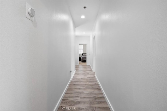 hallway with wood finished floors, baseboards, and recessed lighting