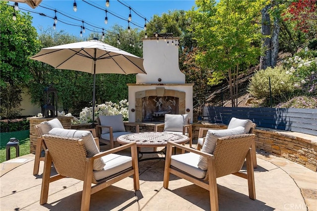view of patio / terrace featuring an outdoor stone fireplace and fence