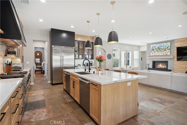 kitchen with a sink, stone tile flooring, extractor fan, high end appliances, and recessed lighting