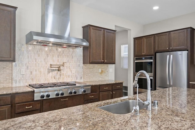 1797 Santa Christina Ave, Chula Vista, CA 91913 - kitchen with wall chimney exhaust hood, appliances with stainless steel finishes, a sink, dark brown cabinets, and light stone counters