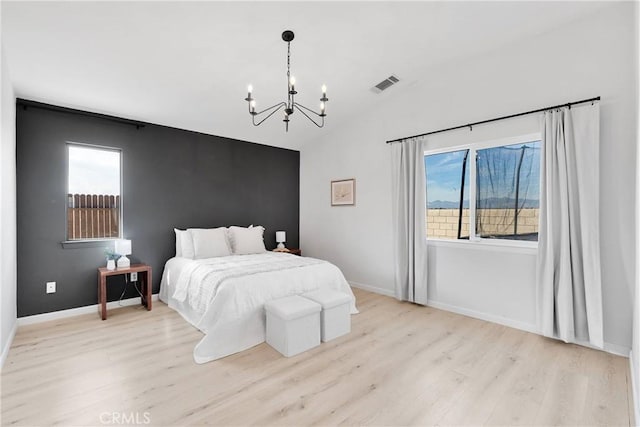 bedroom featuring a chandelier, lofted ceiling, light wood-type flooring, and baseboards