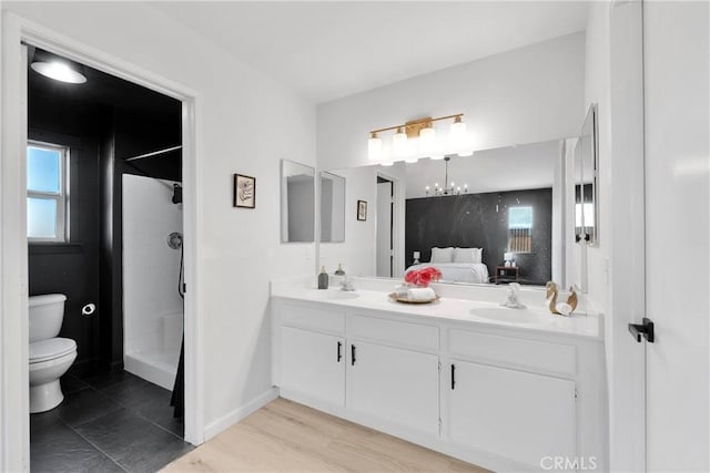 full bath featuring toilet, double vanity, a chandelier, a shower, and connected bathroom