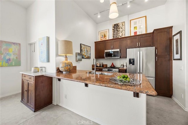 253 N Bush St, Santa Ana, CA 92701 - kitchen featuring appliances with stainless steel finishes, track lighting, stone counters, a breakfast bar area, and a high ceiling