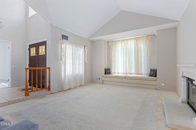 unfurnished living room featuring a glass covered fireplace, carpet, and high vaulted ceiling