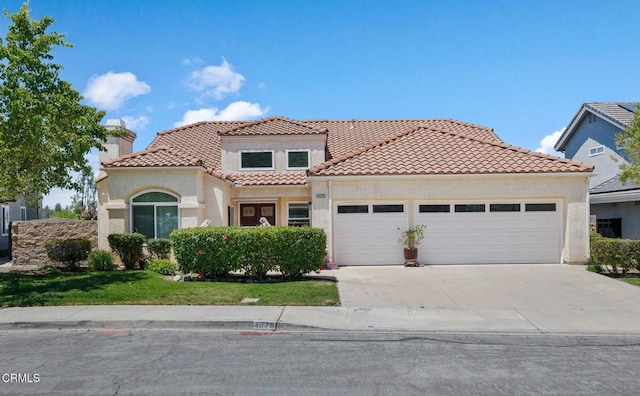 mediterranean / spanish-style home with a garage, stucco siding, driveway, a tile roof, and a front yard
