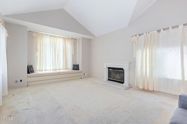 unfurnished living room featuring lofted ceiling, a glass covered fireplace, and carpet flooring