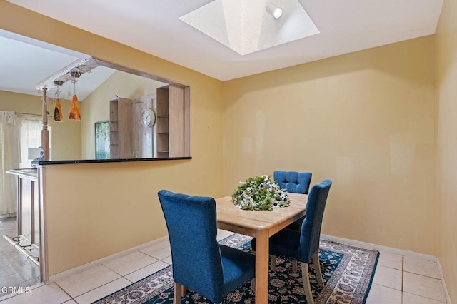 dining area featuring a skylight, light tile patterned floors, and baseboards