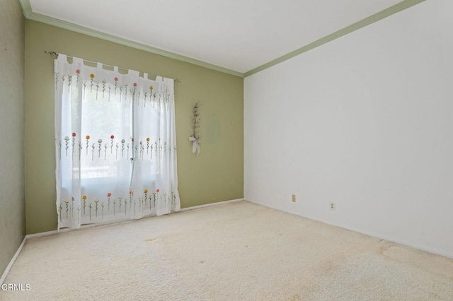 carpeted spare room featuring crown molding and baseboards