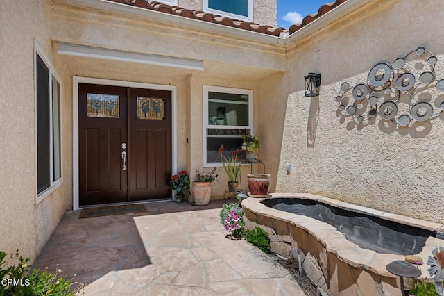 entrance to property featuring a tile roof and stucco siding