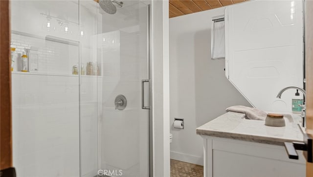 bathroom with a stall shower, vanity, baseboards, and toilet