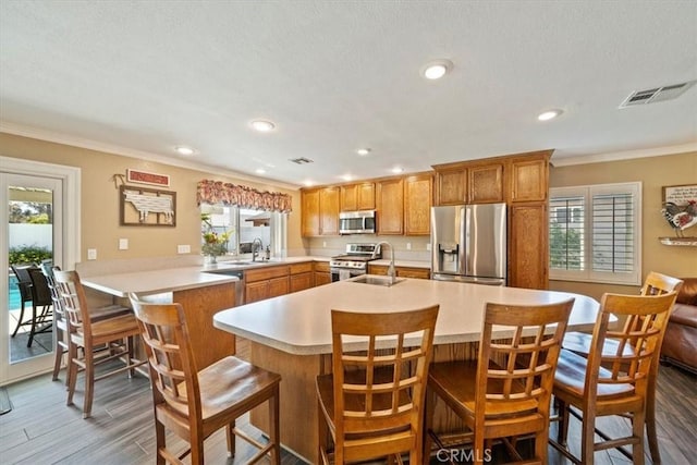 1266 Marina Rd, Corona, CA 92880 - kitchen featuring appliances with stainless steel finishes, light countertops, crown molding, plenty of natural light, and brown cabinetry