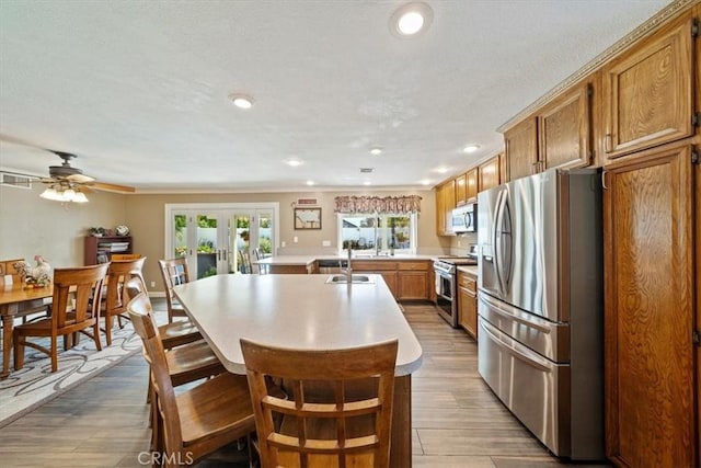 1266 Marina Rd, Corona, CA 92880 - kitchen with stainless steel appliances, light countertops, a kitchen island with sink, french doors, and brown cabinetry