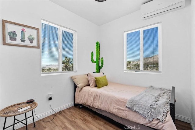 59101 Joshua Dr, Yucca Valley, CA 92284 - bedroom featuring a wall mounted AC, multiple windows, wood finished floors, and baseboards