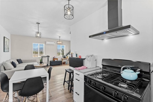 59101 Joshua Dr, Yucca Valley, CA 92284 - kitchen featuring black gas range oven, wall chimney exhaust hood, light wood finished floors, pendant lighting, and open floor plan