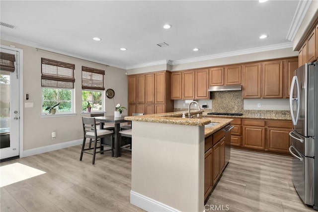 14215 Rolling Stream Pl, Eastvale, CA 92880 - kitchen featuring stainless steel appliances, ornamental molding, light wood-style floors, light stone countertops, and under cabinet range hood
