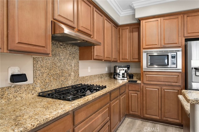 14215 Rolling Stream Pl, Eastvale, CA 92880 - kitchen with stainless steel appliances, under cabinet range hood, ornamental molding, light stone countertops, and light wood-type flooring