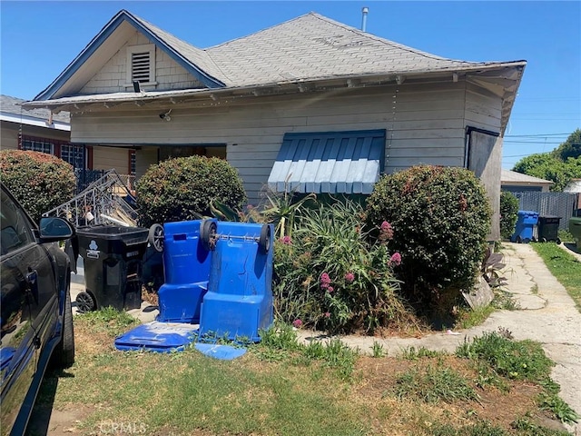 view of side of home featuring an attached garage and a shingled roof