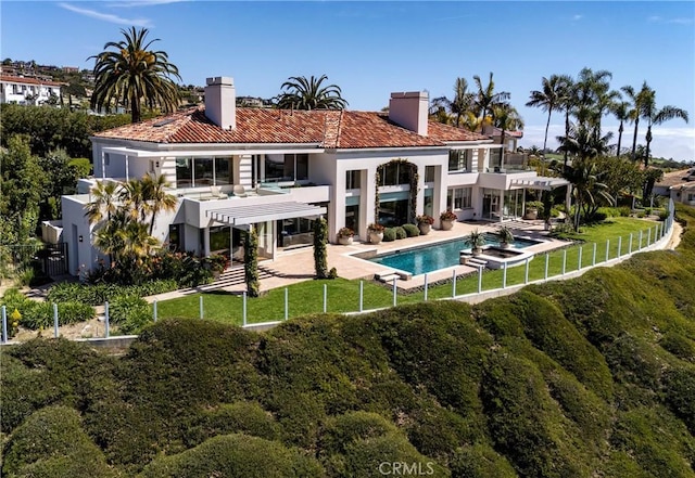 back of property featuring a balcony, stucco siding, a chimney, an outdoor pool, and a patio