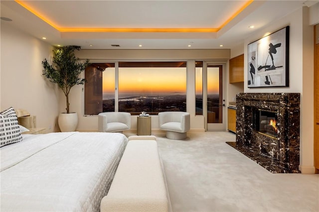 carpeted bedroom with a raised ceiling, a premium fireplace, and recessed lighting