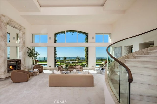 living area with a high ceiling, a high end fireplace, and stairway