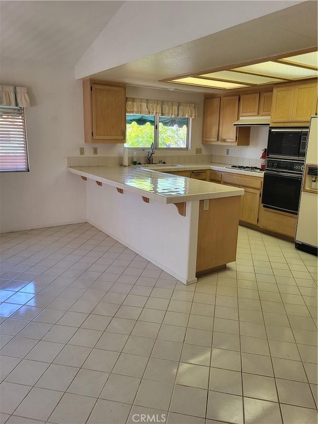 40132 Zamura Ct, Murrieta, CA 92562 - kitchen featuring black appliances, a peninsula, light tile patterned floors, and a breakfast bar