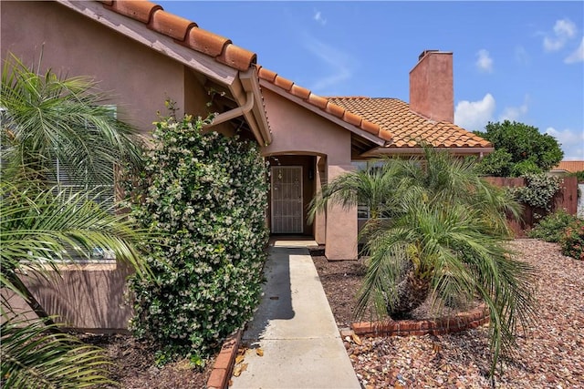 29331 Mawr Ct, Menifee, CA 92586 - view of exterior entry featuring a chimney, a tile roof, and stucco siding