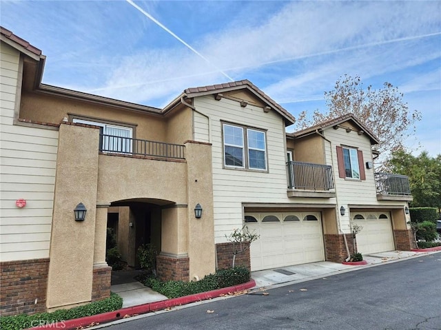 7331 Shelby Pl Unit 121, Rancho Cucamonga, CA 91739 - view of front of property with a balcony, an attached garage, stucco siding, and brick siding