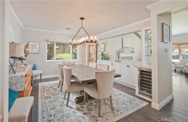 dining area featuring wine cooler, a chandelier, dark wood-style floors, crown molding, and baseboards