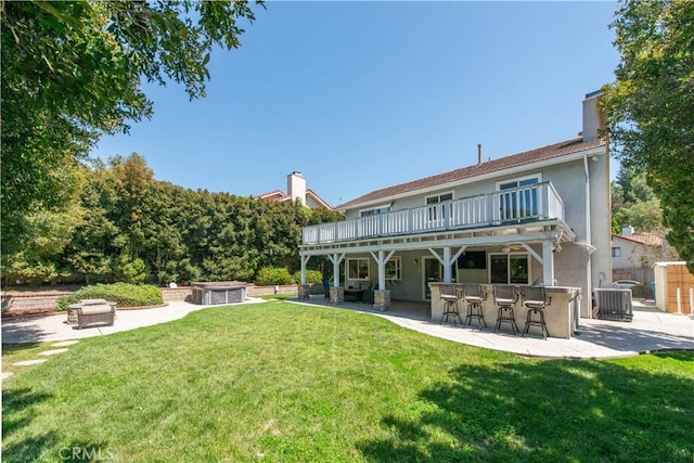 rear view of property featuring stucco siding, a lawn, central AC, and a patio area