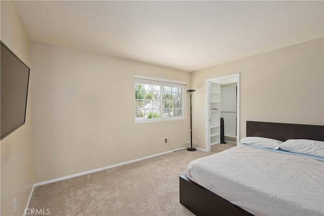 bedroom featuring light carpet, baseboards, and a spacious closet
