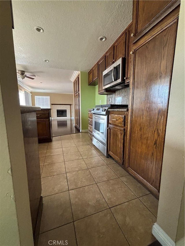 17092 Whispering Brook Way, Riverside, CA 92503 - kitchen with stainless steel appliances, a textured ceiling, tile patterned floors, dark countertops, and baseboards