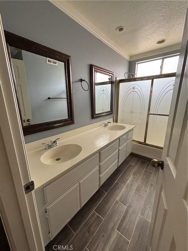 17092 Whispering Brook Way, Riverside, CA 92503 - full bathroom featuring crown molding, a textured ceiling, wood finish floors, double vanity, and bath / shower combo with glass door