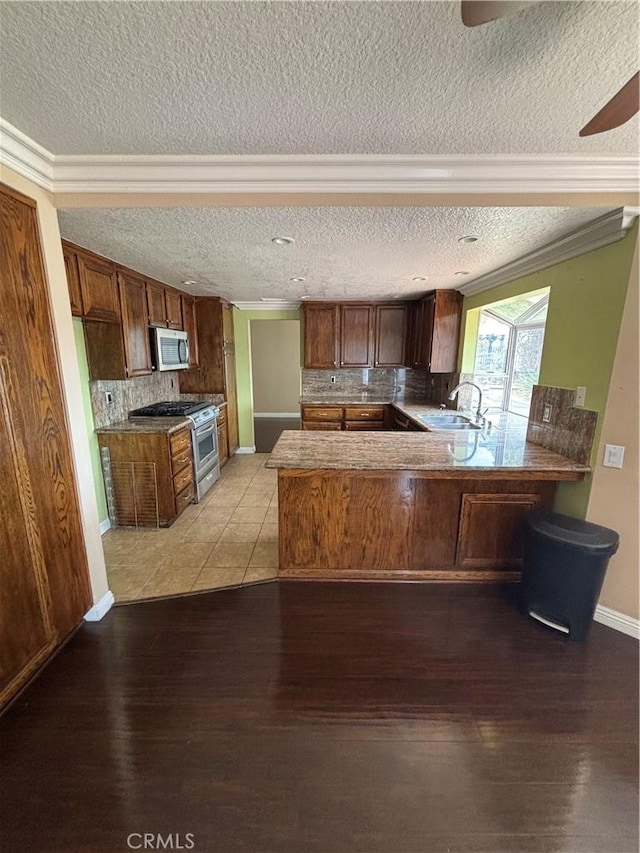 17092 Whispering Brook Way, Riverside, CA 92503 - kitchen with appliances with stainless steel finishes, a textured ceiling, a peninsula, tasteful backsplash, and light wood-style flooring