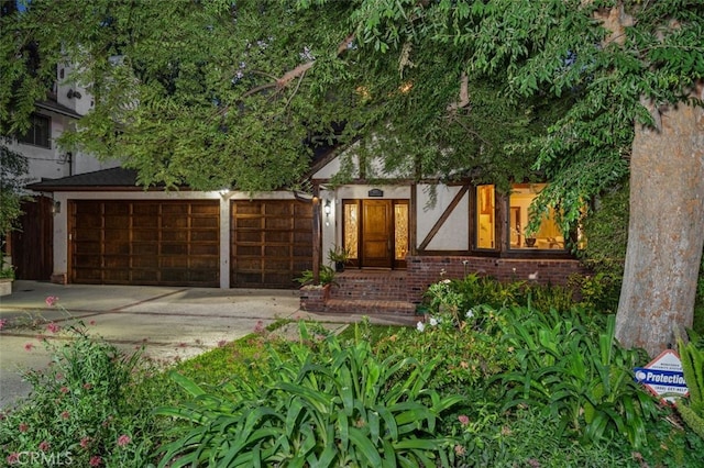 view of front of house with driveway, a garage, brick siding, and stucco siding