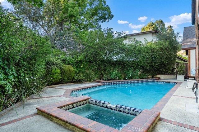 view of pool with a fenced backyard and a pool with connected hot tub