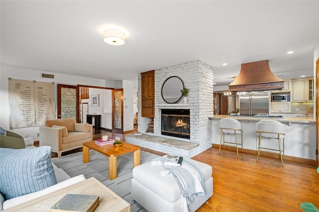 living room with light wood finished floors, a fireplace, and baseboards