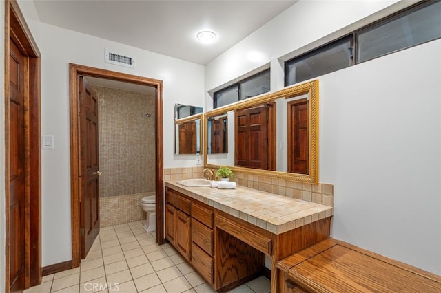 bathroom featuring toilet, tile patterned flooring, a shower, vanity, and tasteful backsplash