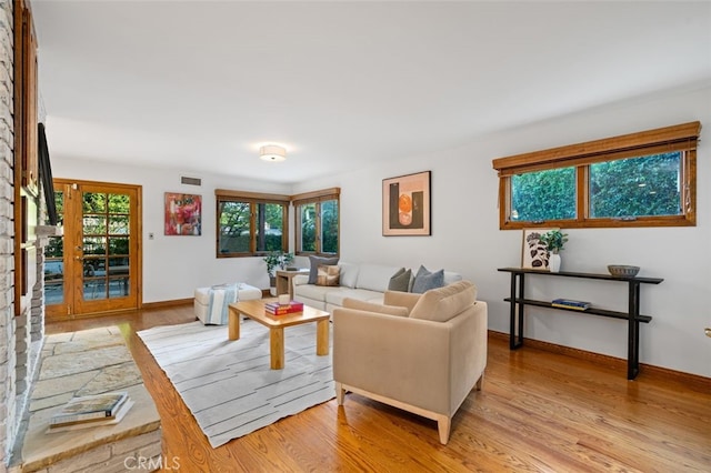 living area with light wood-style flooring, baseboards, and french doors