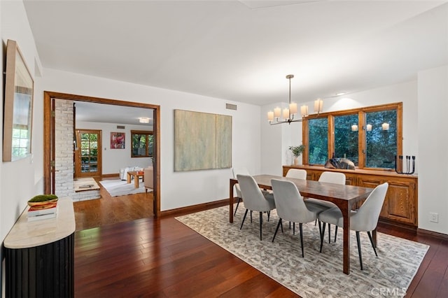 dining space with a chandelier, dark wood finished floors, and baseboards