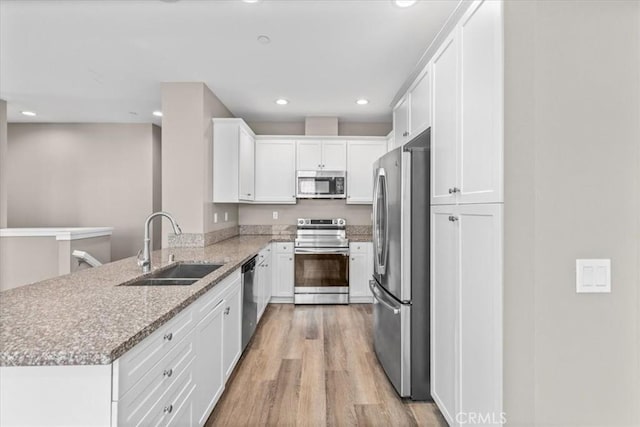 7501 Eagle Dr Unit 101, Santee, CA 92071 - kitchen featuring stainless steel appliances, a sink, a peninsula, light wood-type flooring, and white cabinetry