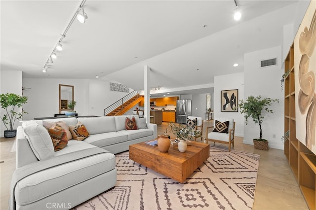 living area with track lighting, stairs, concrete flooring, and recessed lighting
