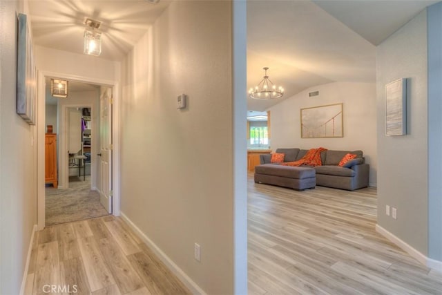324 Crater Lake Dr, Chico, CA 95973 - corridor with vaulted ceiling, light wood finished floors, a chandelier, and baseboards