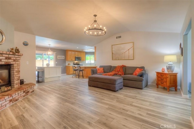 324 Crater Lake Dr, Chico, CA 95973 - living area featuring a chandelier, light wood-style flooring, a brick fireplace, lofted ceiling, and baseboards