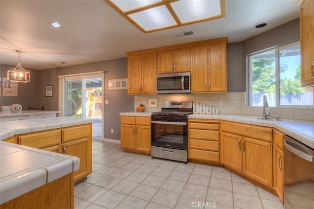 324 Crater Lake Dr, Chico, CA 95973 - kitchen featuring appliances with stainless steel finishes, a sink, backsplash, tile counters, and a chandelier