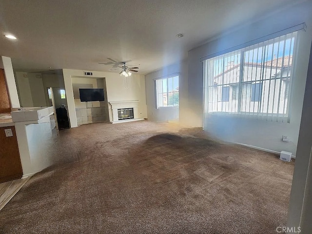 unfurnished living room featuring a glass covered fireplace, ceiling fan, carpet flooring, and recessed lighting